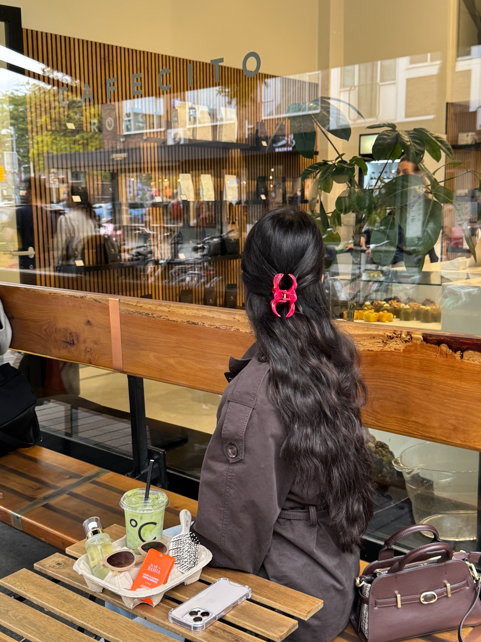 Vrouw met RĀUVV arganolie op tafel bij een café